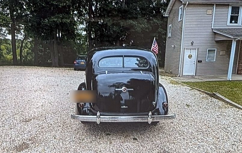 Rear view of a black 1936 Buick Roadmaster Series 80 sedan showing the built-in trunk and chrome bumper